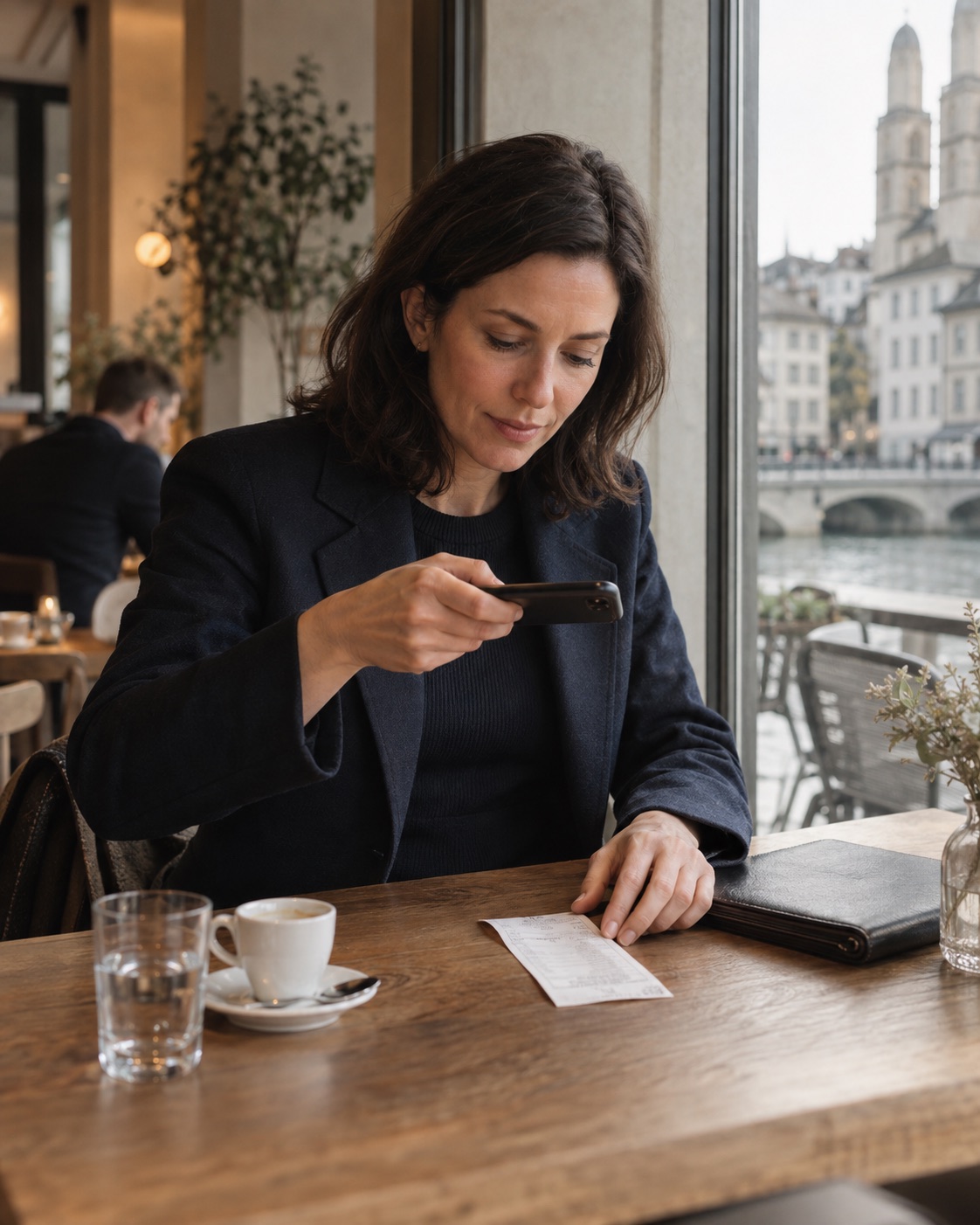 A business traveller photographing a cafe receipt with her phone.